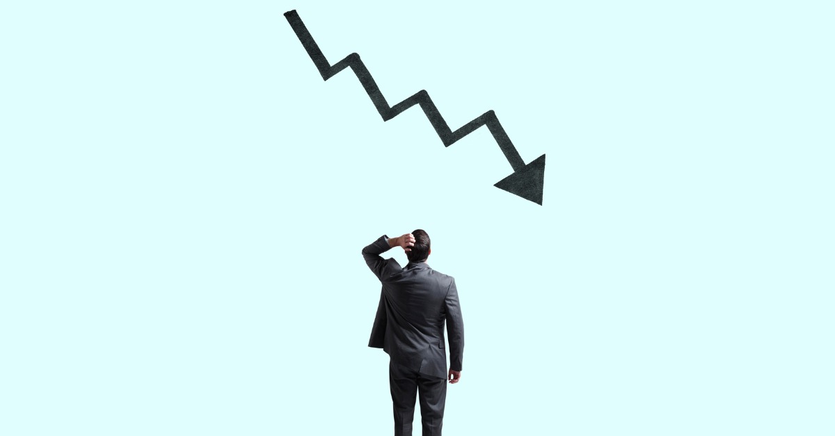 Man standing in front of decreasing profit graph