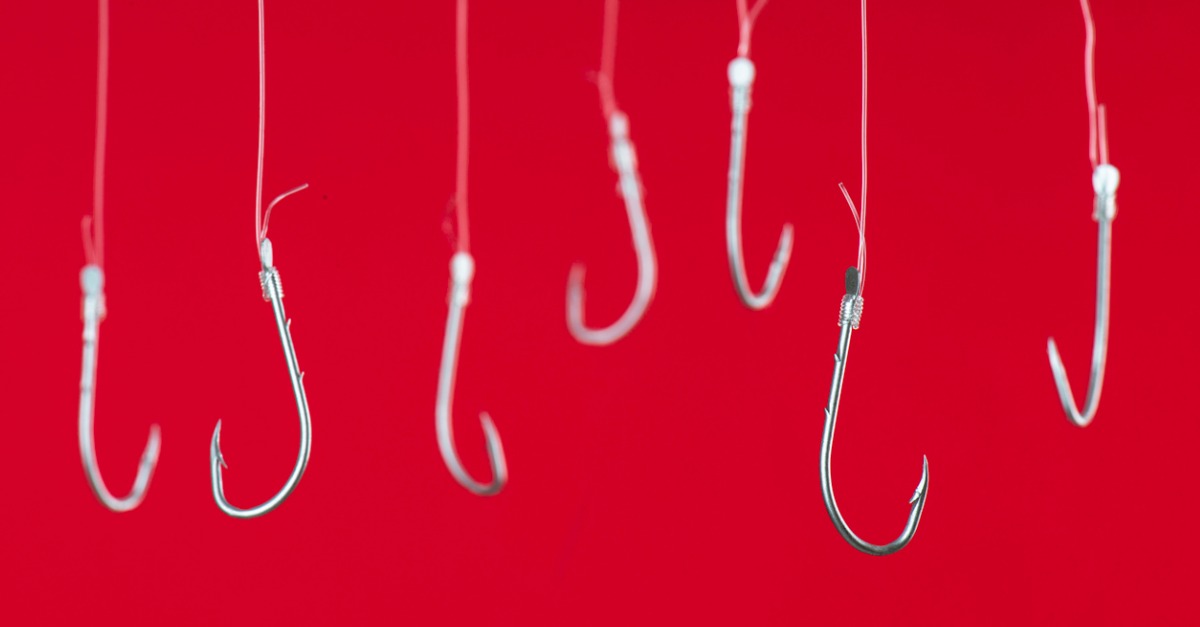 Fish hooks hanging in front of red background