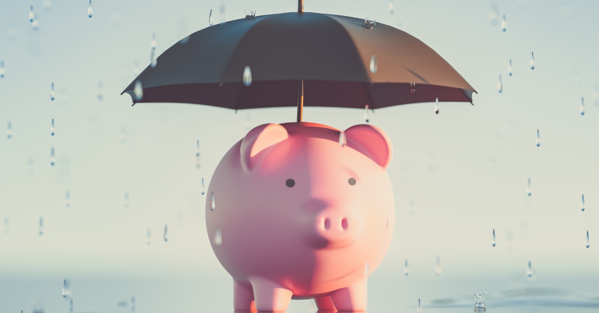 An umbrella over a piggy bank standing in the rain