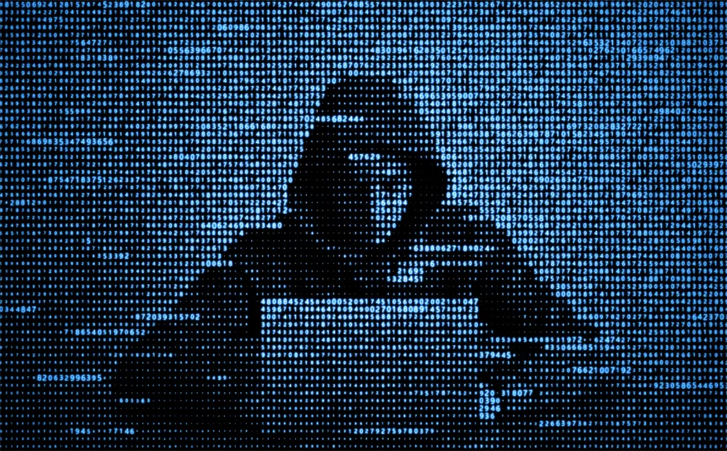 Anonymous figure in hoodie at computer